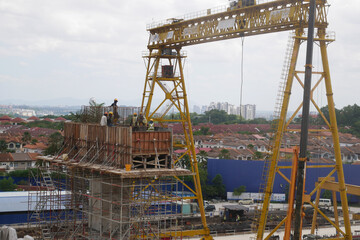 Fototapeta na wymiar SEREMBAN, MALAYSIA -MARCH 29, 2020: Construction workers fabricating steel reinforcement bar at the construction site. They tied it together using the tiny wires. It is one of the steps in making of r