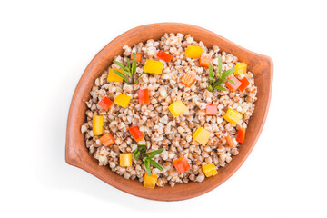 Buckwheat porridge with vegetables in clay bowl isolated on white background. Top view, close up.