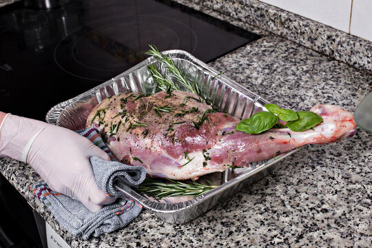 Meat steak baked in foil with fresh herbs and vegetables.  Woman's hand gets out of the oven. 
oven-cooked meat