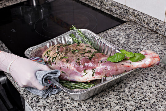 Meat steak baked in foil with fresh herbs and vegetables.  Woman's hand gets out of the oven. 
oven-cooked meat
