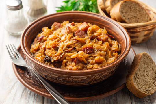 Traditional Polish dish Bigos in ceramic bowl on rustic wooden table