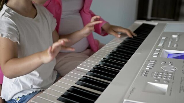 Private music teacher giving piano lessons to little girl. Hands close up.