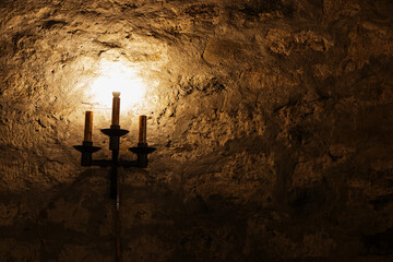A candlelight lamp on a stone wall in the medieval style, lighting in a dark castle.