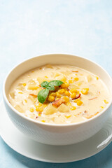 Corn chowder soup in white bowl on concrete background