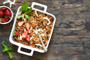 Granola with nuts, coconut and berries in a baking dish on a wooden background. Top view.