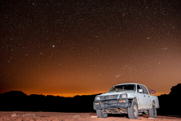 Clear night sky with stars above truck in Wadi Rum desert in Jordan