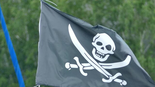 Black pirates flag with swords and scull waving in the wind
