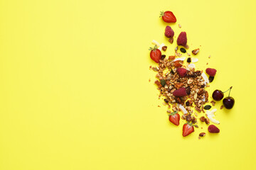 Granola with nuts and berries on a yellow background. View from above.