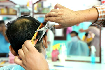 An Indian male in mask getting hair cut in beauty saloon with proper safety measures for Covid-19....