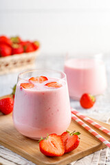 Glass with strawberry smoothie or milkshake on wooden table. Summer drink.