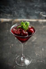 Cherry cocktail in martini glass with berries and mint leaves. Selective focus. Shallow depth of field.