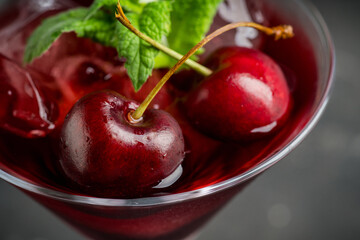Cherry cocktail in martini glass with berries and mint leaves. Selective focus. Shallow depth of field.
