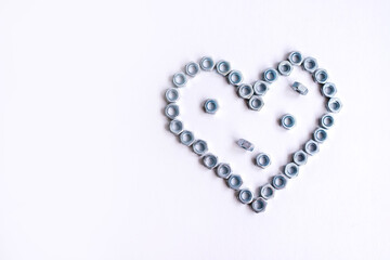 Fototapeta na wymiar Heart laid out of bolts, nuts on a white background. Father's Day and wedding anniversary concept.