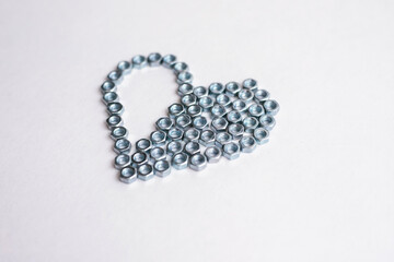 Heart laid out of bolts, nuts on a white background. Father's Day and wedding anniversary concept.