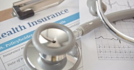 Health insurance form on a table in a doctor or physician office. Stethoscope on an insurance agreement, paper that has a plan or policy covers or insure the risk of a person incurring medical expense