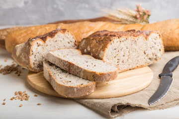 Sliced bread with different kinds of fresh baked bread on a white wooden background. side view, selective focus.