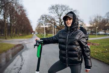 Woman in a jacket on an electric scooter in an autumn park.