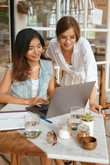 Women Working At Cafe. Girls In Casual Clothes Using Laptop And Having Discussion About Business. Modern Digital Nomad Lifestyle With Technologies For Creativity Online Job.