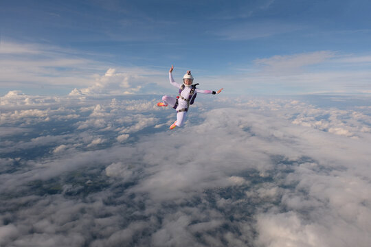A beautiful girl is flying in the sky above white clouds.