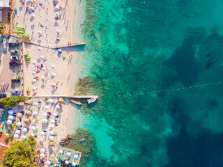 Top down view of a beautiful white sand beach with turquoise water and relaxing people on a sunny day. Ksamil, Albania.