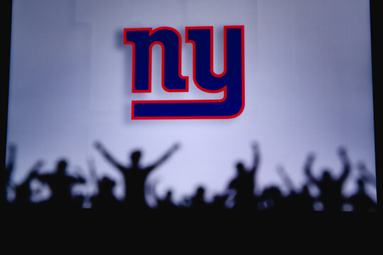 New York Giants. Fans support professional team of American National Foorball League. Silhouette of supporters in foreground. Logo on the big screen.