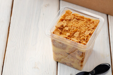 Creamy dessert in a plastic box on wooden table