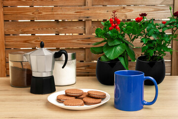 Good morning with coffee. A cup of coffee in blue. Biscuits. Coffee maker.. Sunny.