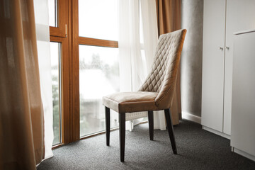 Brown chair standing near large window in room