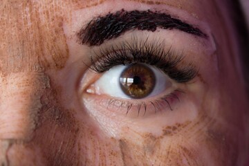 Beauty day. Close-up of a woman`s face. The woman has a clay face mask and eyebrows painted black.