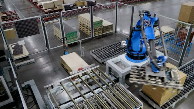 Furniture factory. A modern automated machine packaging furniture parts in cardboard boxes. 4K