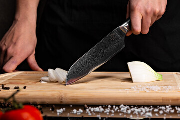 Closeup of hands of chef cook cutting vegetables on wooden table