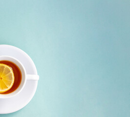 A Cup of tea with lemon and mint. Empty space for text. Isolated on a light blue background