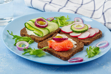 Appetizer, open sandwich with salmon on a blue plate on white background. Traditional Italian or Scandinavian cuisine. Concept of proper nutrition and healthy eating. Close up