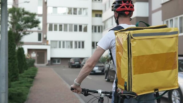 Food delivery in a yellow backpack on a bicycle during the quarantine period. Coronavirus, COVID-19, safe delivery.
