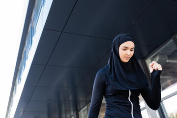 muslim sportswoman in black hijab near building