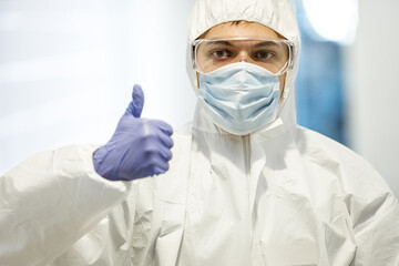 Fototapeta premium corona virus concept. male scientist doctor in mask, glasses and protective suit showing thumb up and getting ready for COVID-19 pandemic outbreak quarantine