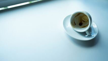 white cup and plate with coffee stain on white table beside window light cool tone stock photo