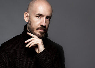 Obraz premium Fashion Portrait of a 40-year-old man standing over a light gray background in a black sweater. Close up. Classic style. Bald shaved head. Copy-space. Studio shot