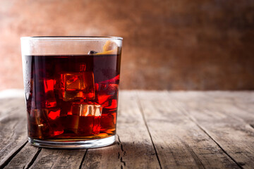 Boulevardier cocktail and orange zest in glass on wooden table. Copy space