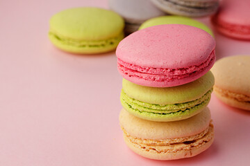 Pile of colorful macaroon cookies on pink background