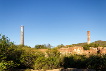 Disused La Ramona and Julia brick smokestacks, next to industrial mining ruin, two historic monuments in El Triunfo, Baja California Sur, Mexico