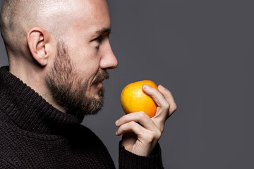 Fashion Portrait of a 40-year-old man standing over a light gray background in a black sweater. Close up. Classic style. Bald shaved head. Copy-space. Studio shot