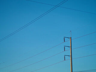 The high voltage light pole fastened to multiple wires leading to On the background is a blue sky