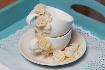 Cups and saucers decorated with polymer clay roses. Handmade white polymer clay jewelry.