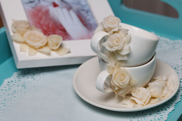 Cups, saucer, and photo frame painted with polymer clay roses. Handmade white polymer clay jewelry.