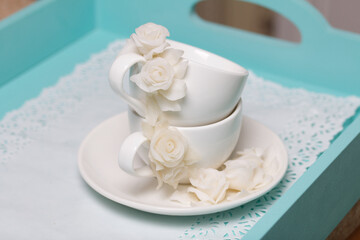 Cups and saucers decorated with polymer clay roses. Handmade white polymer clay jewelry.