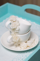 Cups and saucers decorated with polymer clay roses. Handmade white polymer clay jewelry.