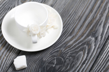 Handmade cups and saucers decorated with polymer clay roses. Near a piece of polymer clay. Jewelry made of white polymer clay.