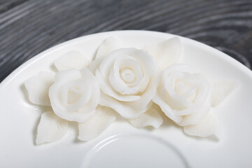 Handmade saucer decorated with polymer clay roses. Jewelry made of white polymer clay. Close up shot/