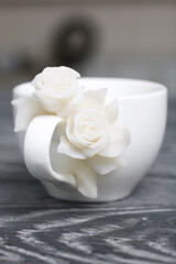 Handmade cup decorated with polymer clay roses. Jewelry made of white polymer clay.
